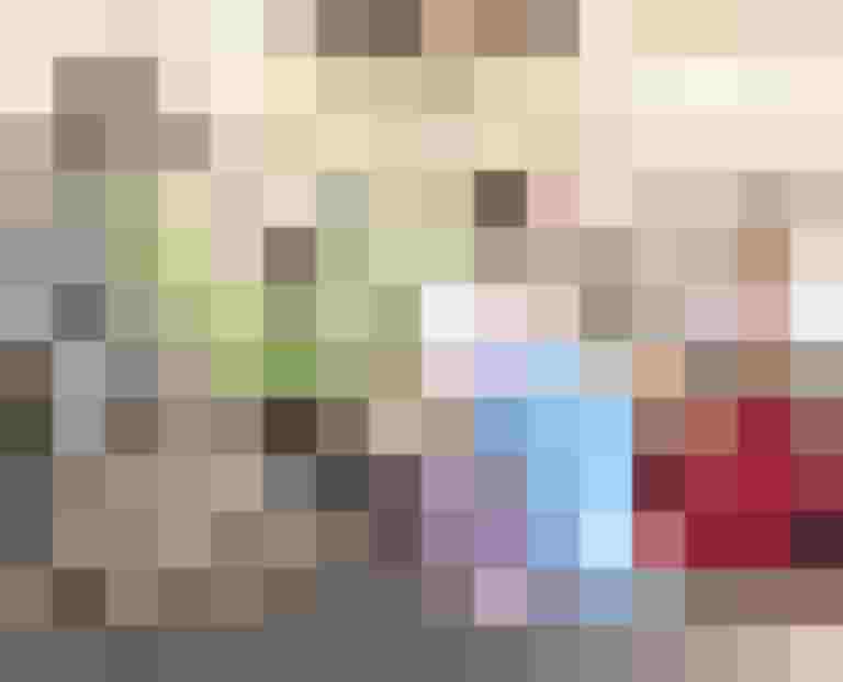 Zwei Frauen in Trachten sitzen lächelnd neben Fahrrädern vor einer Steinmauer.