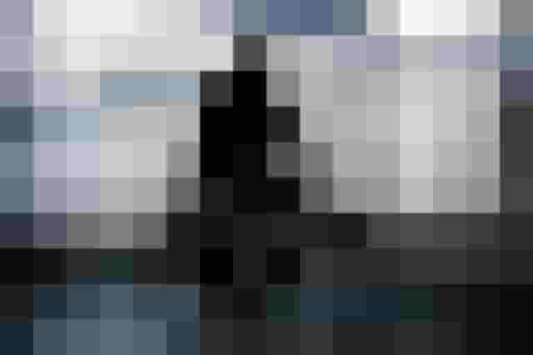 Radfahrer mit Regenschirm fährt bei Nieselregen durch eine Stadtstraße.