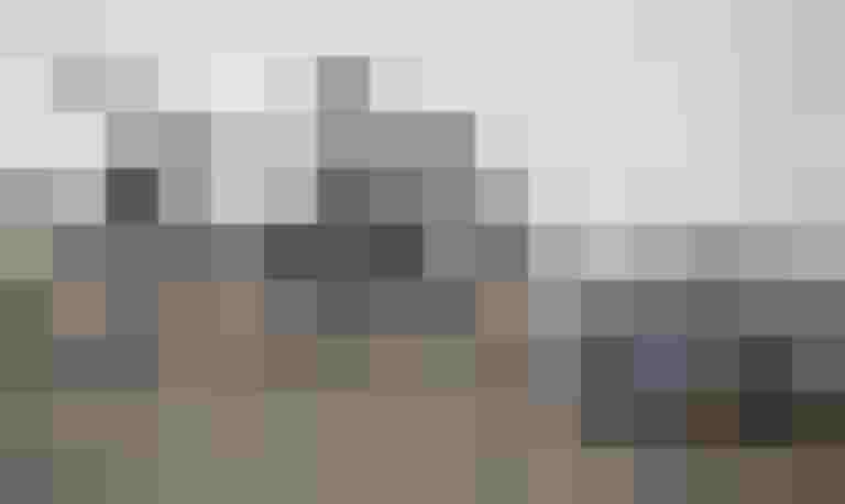 Schwarzes Fahrrad mit silbernem Lastenanhänger auf Pflasterboden.