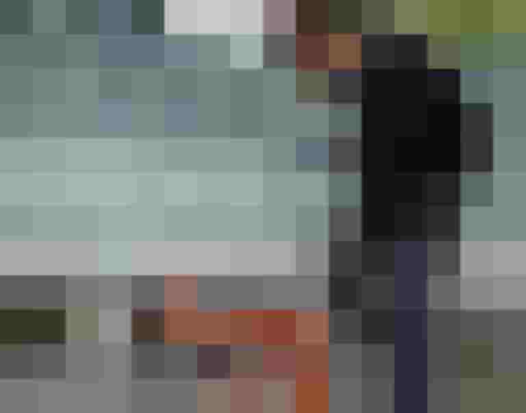 Mann faltet ein orangefarbenes Fahrrad vor einer Wand in Salzburg.