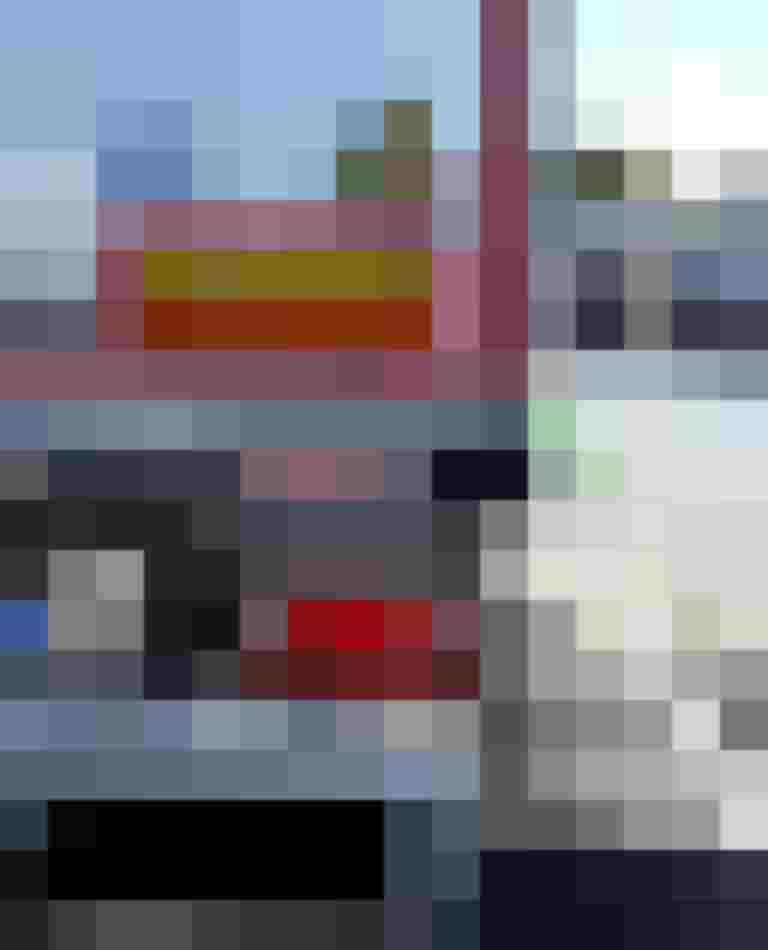 Warnhinweis „Achtung: Toter Winkel“ auf einem LKW, im Hintergrund Personen bei einer Veranstaltung.