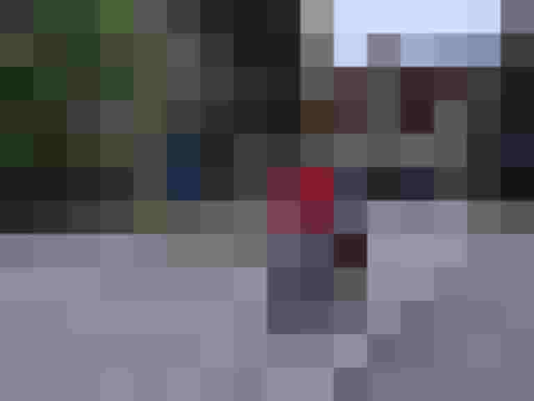 Frau mit Lastenrad auf Straße in Salzburg, umgeben von Bäumen und Häusern.