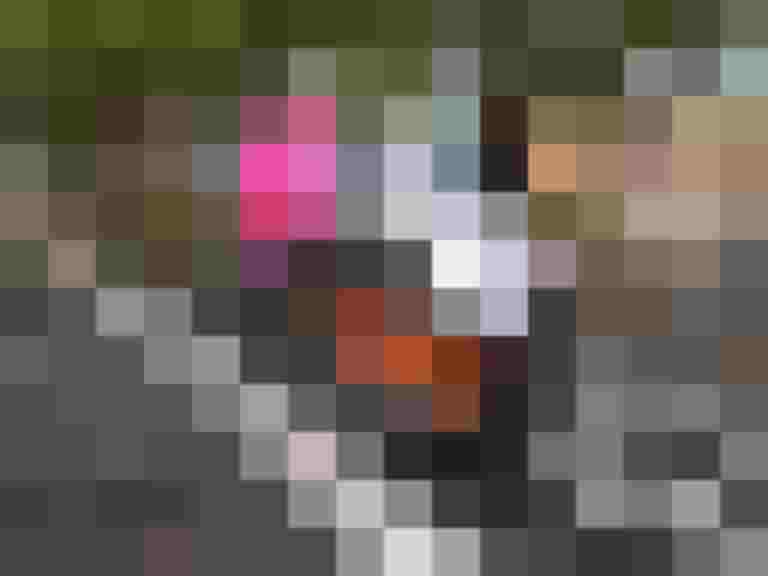Frau in pinker Jacke steht neben einem Cargobike auf einer Straßenfläche mit Laub.