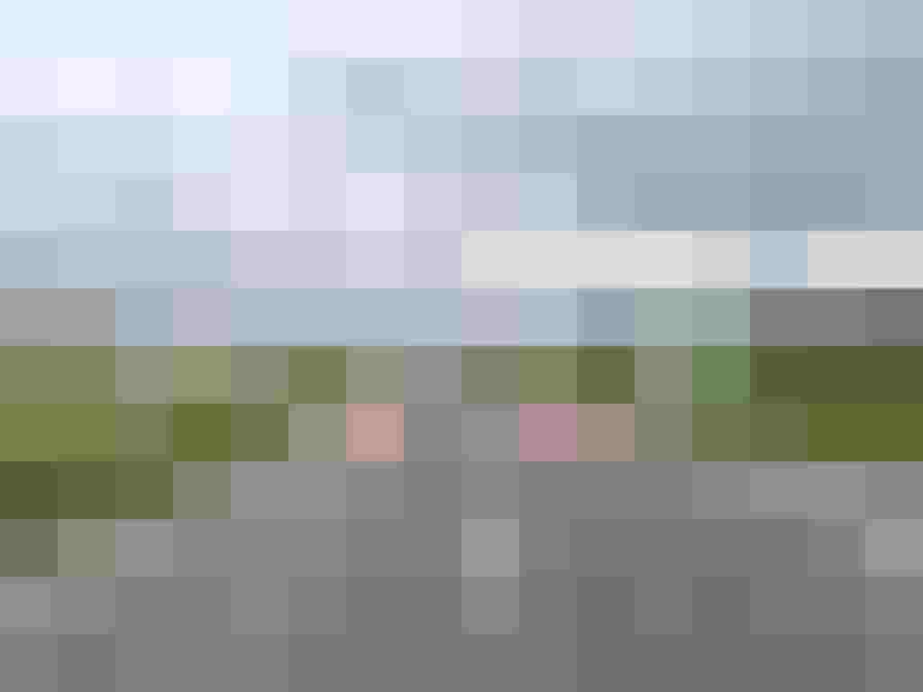 Landstraße mit rot markierten Radstreifen in ländlicher Umgebung unter bewölktem Himmel