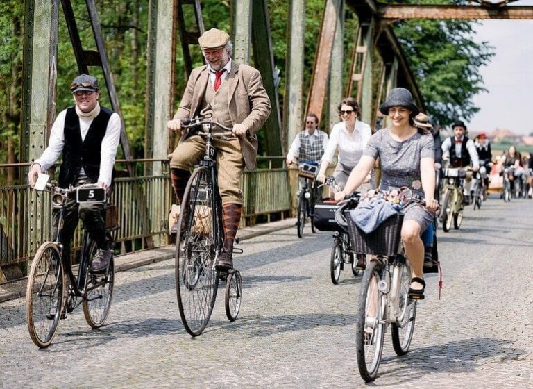 Fahrradfahrer in eleganter Kleidung auf einer Brücke beim Tweed Ride Salzburg.