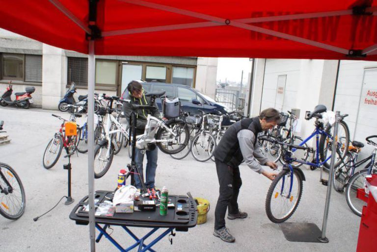 Kostenloser Radcheck in Anthering mit zwei Personen, Werkzeug und vielen Fahrrädern im Hintergrund.
