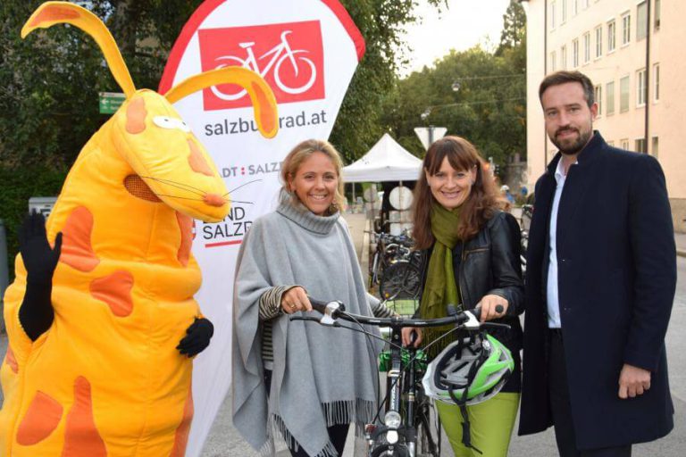 Sitzend mit Fahrrad und Geschenken, Aktion zur Wertschätzung des Radverkehrs in Salzburg.
