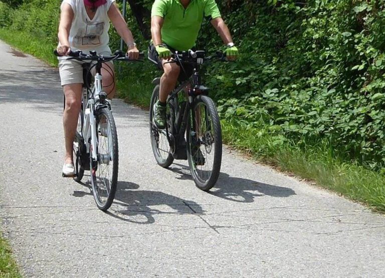 Radfahrende auf einem Weg in Salzburg, umgeben von grüner Natur.
