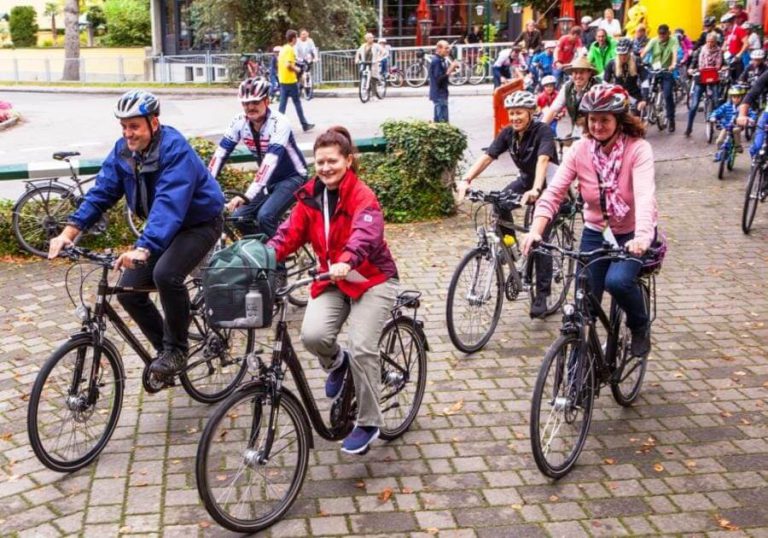 Teilnehmer des Familienradtags in Wals fahren fröhlich auf ihren Fahrrädern.