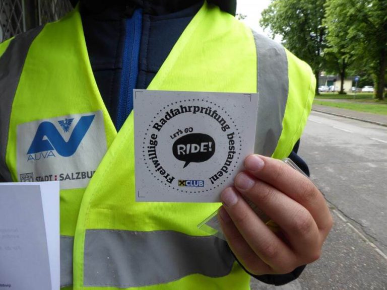 Freiwillige Radfahrprüfung mit einem Flyer in der Hand, begleitet von einer Warnweste.