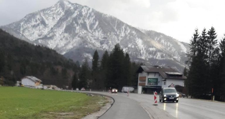 Radweg-Lückenschluss in Ebenau, Schneeberge im Hintergrund, Straßenansicht mit Fahrzeugen.