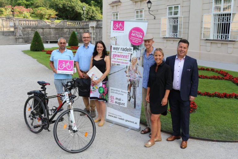 Gewinner der Zwischenverlosung „wer radelt gewinnt“ posieren mit Fahrrad und Plakaten.