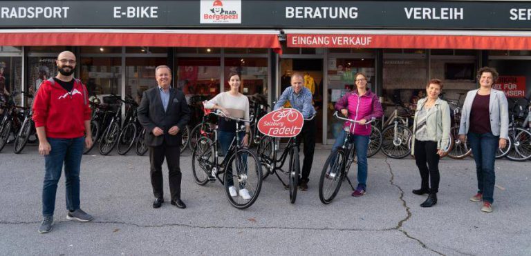 Gruppe von Menschen mit Fahrrädern vor einem Fahrradgeschäft in Salzburg.