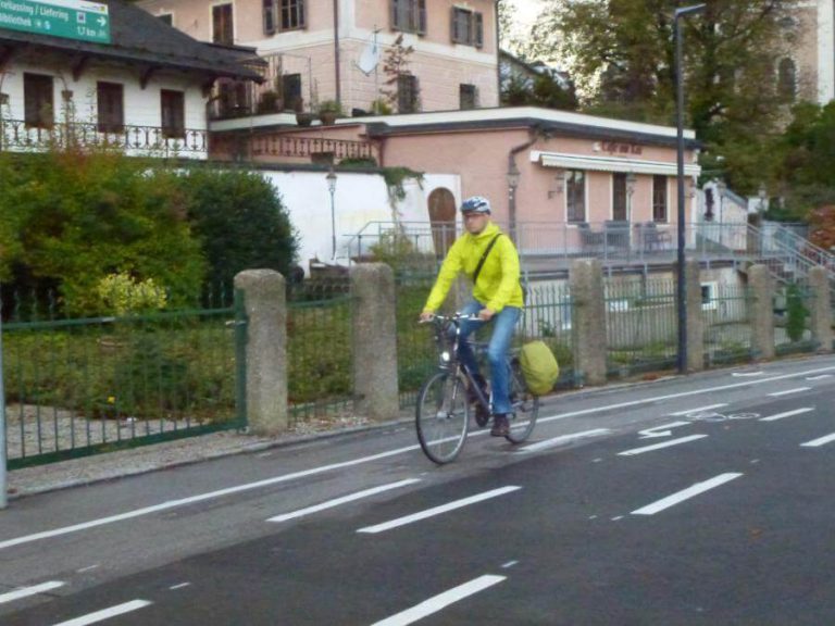 Fahrer im leuchtend gelben Outfit auf Radweg in Salzburg, unterwegs im Alltag.