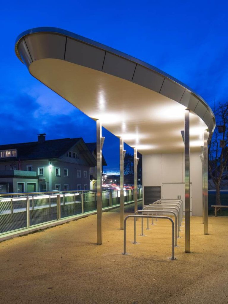 Überdachte Radabstellanlage an Haltestelle bei Nacht, gefördert für bessere Mobilität in Salzburg.