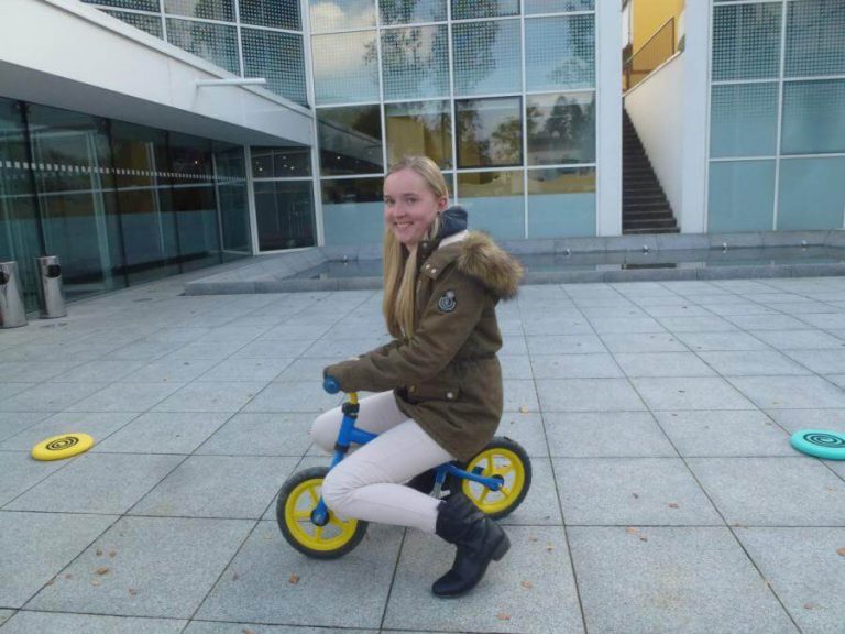 Junge Frau fährt auf einem Laufrad in einem modernen Außenbereich.