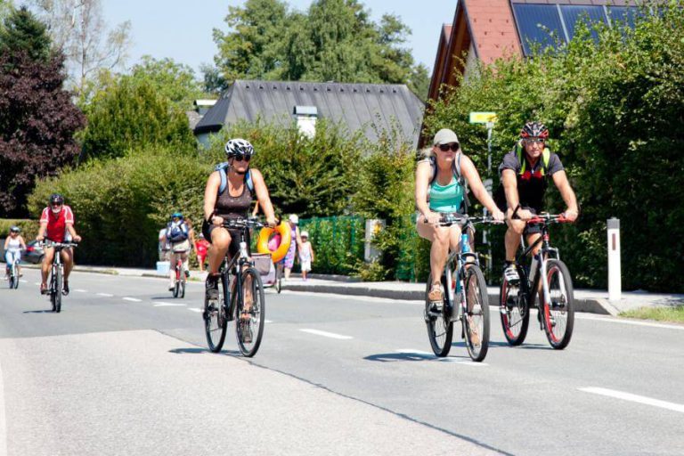 Radfahrer genießen den motorfreien Tag am Obertrumer See mit sonnigem Wetter.