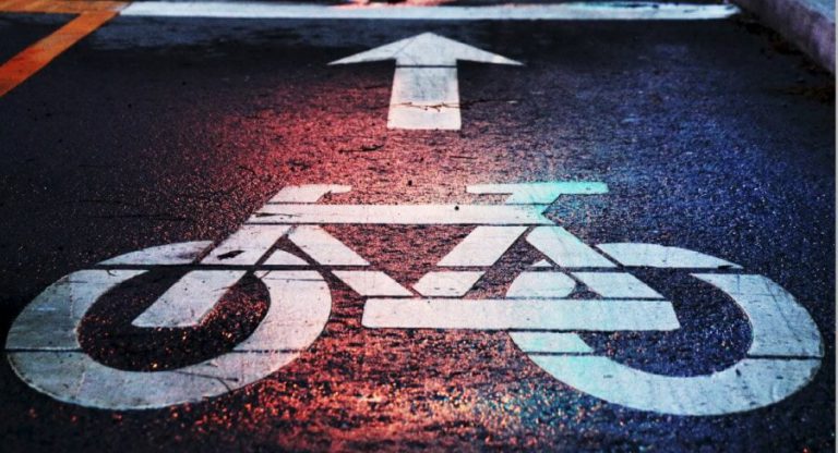 Fahrradzeichen auf asphaltierter Fläche mit Pfeil nach vorne, Symbol für Radverkehr.