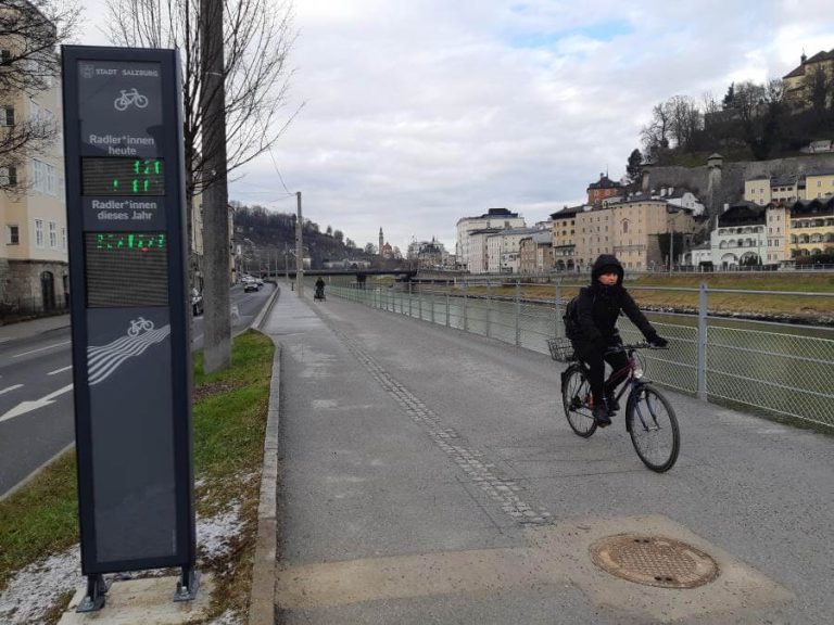 Rad-Stele am Rudolfskai zeigt aktuelle Radfahrerzahlen an, Radfahrender fährt vorbei.