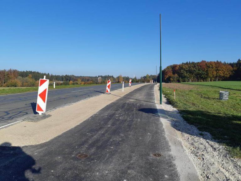Neuer Geh- und Radweg an der L115 mit Warnschildern und Umgebungsgrün.