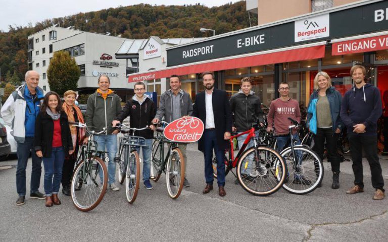 Teilnehmer der Preisübergabe „Salzburg radelt“ mit Fahrrädern vor einem Radgeschäft.