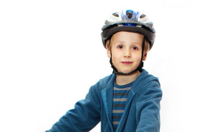 Junger Junge mit Helm, bereit zum Radfahren, im Kontext von Fahrradkursen für Kinder.