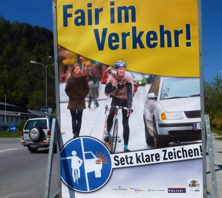 Plakat für Verkehrssicherheit mit Radfahrer, Fußgänger und Botschaft zu fairem Verkehr.