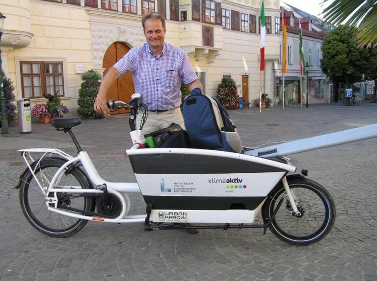 Mann mit Lastenrad in einer urbanen Umgebung, geprägt von nachhaltiger Mobilität.