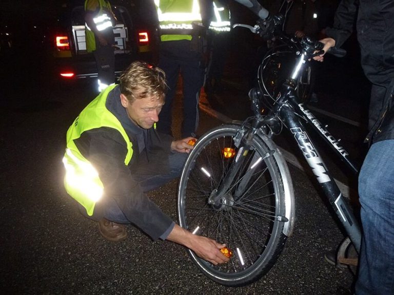 Person montiert Reflektoren an einem Fahrrad während der Radlichtaktion in Salzburg.