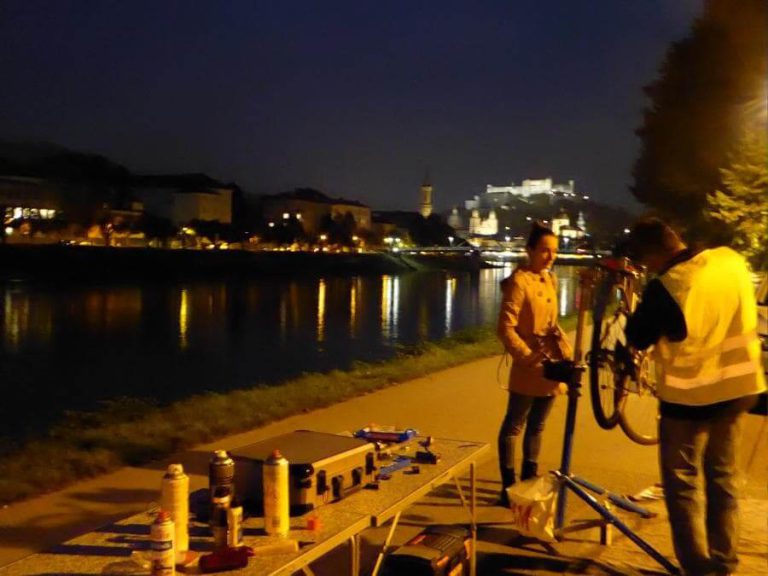 Personen überprüfen ein Fahrrad bei einer Radlichtaktion in Salzburg am Abend.