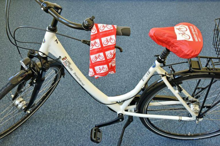 Weißes Fahrrad mit rot-weißem Sattelbezug, Branding von SalzburgRad.