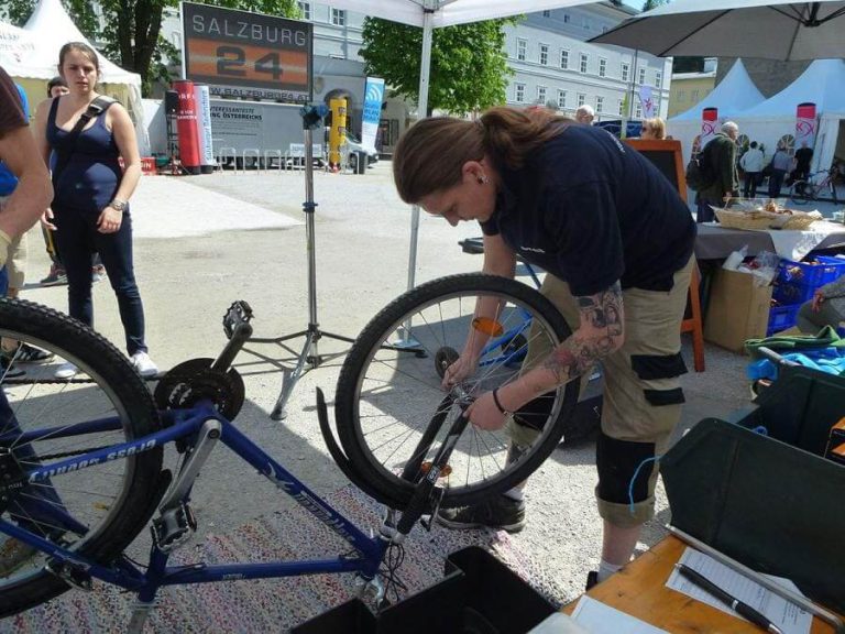 Fachmann repariert ein Fahrradrad beim Repair Café in Salzburg.