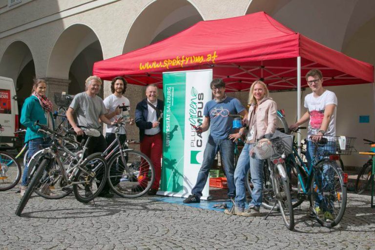 Gruppe von Radfahrern vor einem Zelttstand für Radservice und Anleitungen in Salzburg.