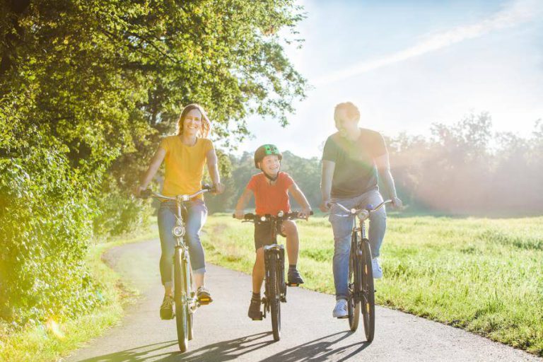 Familie radelt entspannt auf einem Weg durch die Natur in Salzburg.