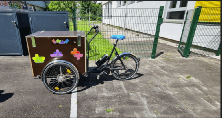 Lastenrad mit bunten Aufklebern steht zum kostenlosen Ausleihen in Salzburg bereit.