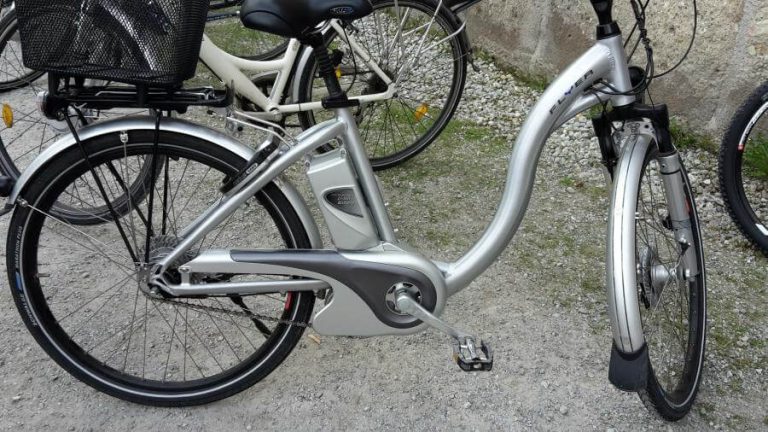 Silbernes Elektro-Fahrrad auf Kiesweg, bereit fürs Einwintern und Pflege.