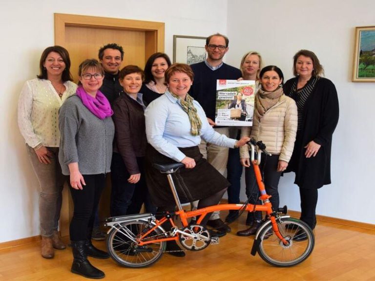 Gruppenfoto beim Treffen „Wer radelt gewinnt“ mit einem orangefarbenen Fahrrad.