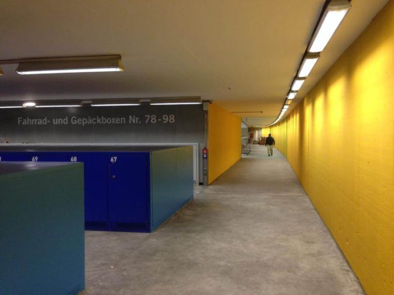 Radgarage am Salzburger Hauptbahnhof mit blauen Radboxen und gelbem Wandteil.