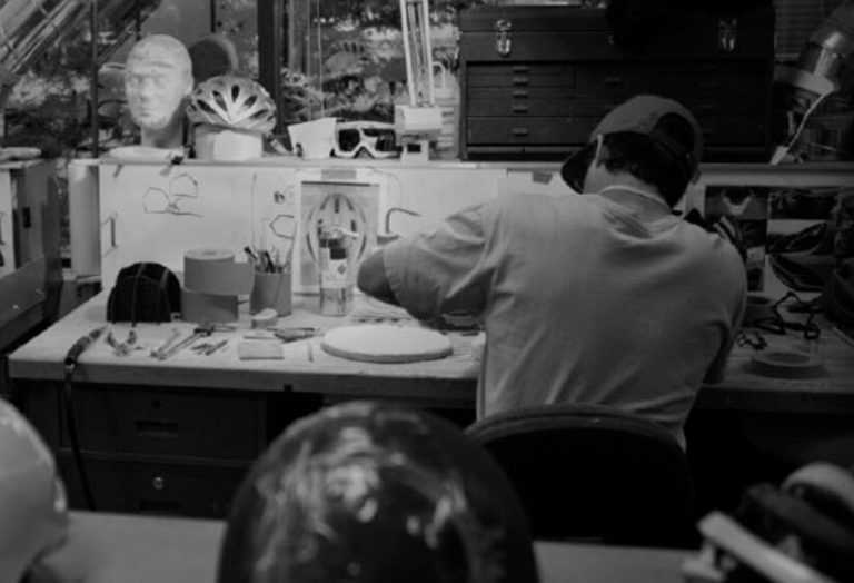 Person arbeitet an Helmen an einem Tisch voller Werkzeuge und Materialien.