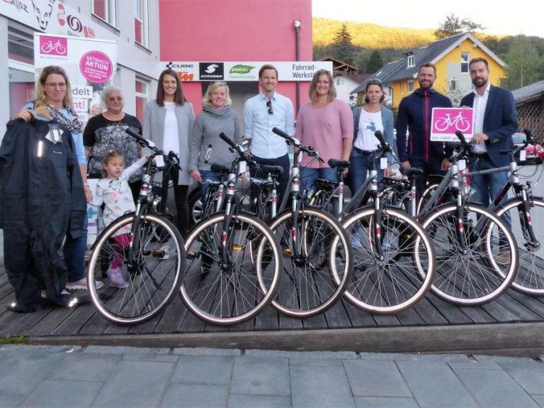 Gewinner der Aktion „wer-radelt-gewinnt“ stehen mit Fahrrädern und Preisen zusammen.
