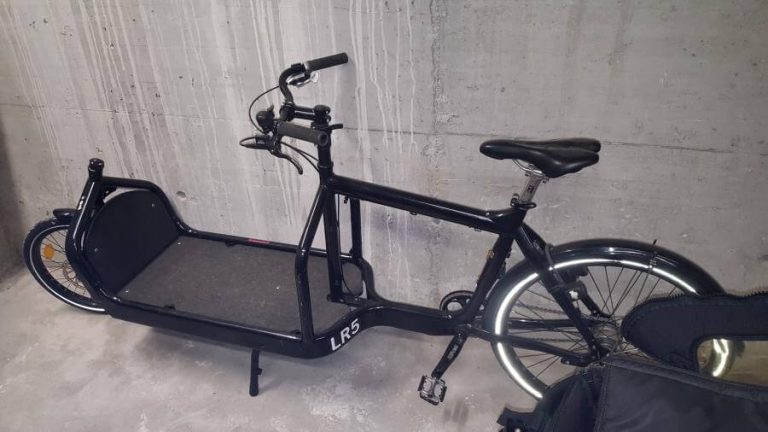 Schwarzes Lastenrad in einem Parkhaus, bereit für den Verleih in Salzburg.