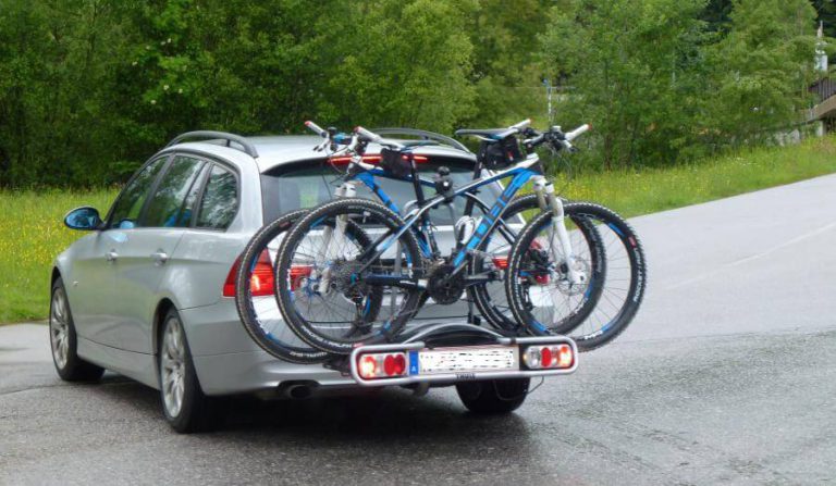 Rotes Kennzeichen für Rad-Heckträger an einem Auto mit zwei Mountainbikes.