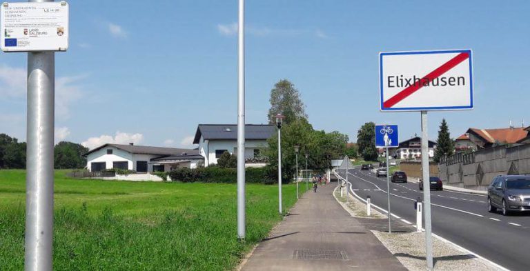 Geh- und Radweg in Elixhausen mit Verkehrsschildern und angrenzenden Wohnhäusern.