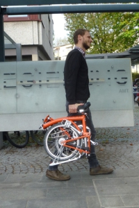 Mann trägt zusammengefaltetes Faltrad