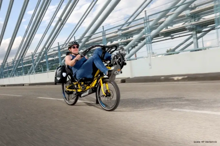 Liegeradfahrer auf einer Brücke, betont umweltfreundliche Mobilität in Salzburg.