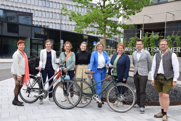 Gruppenfoto von Personen mit Fahrrädern vor einem modernen Gebäude in Salzburg.