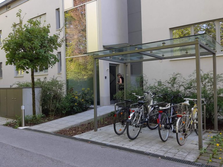Überdachte Fahrradabstellanlagen vor einem modernen Gebäude in Salzburg.