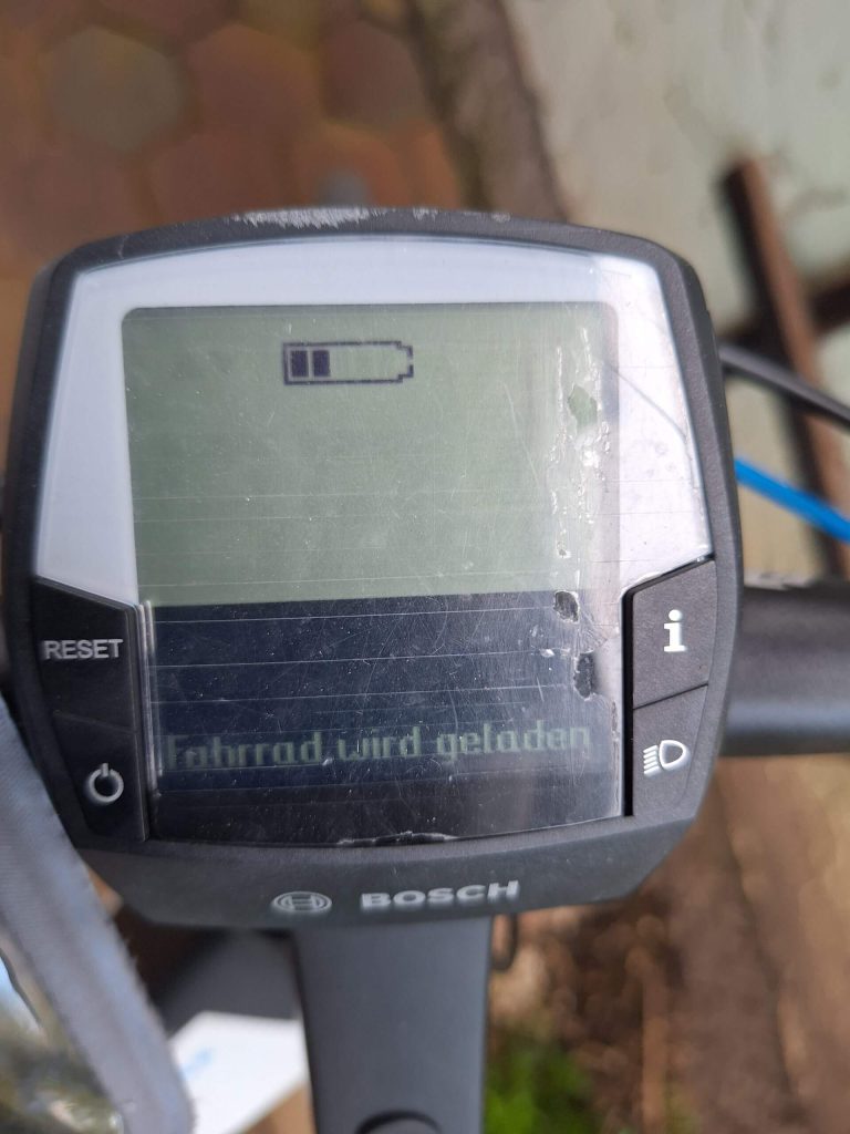 Display eines E-Bikes zeigt "Fahrrad wird geladen" und Batteriesymbol.
