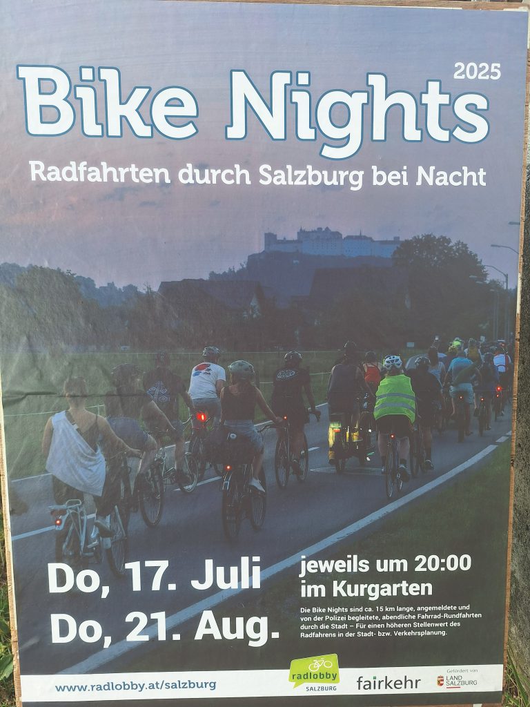 Gruppe von Radfahrenden bei Nacht auf beleuchteter Straße in Salzburg unterwegs