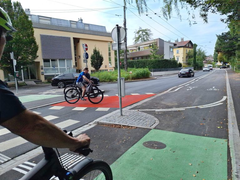 Radweg in Salzburg mit Radfahrern, grünen und roten Fahrbahnmarkierungen.